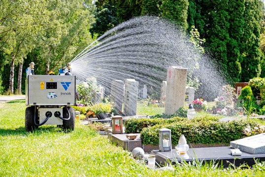 Der Gie�roboter RAINOS beim autonomen Bew�ssern eines Grabs.