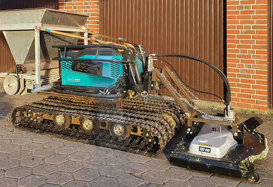 Moosdosierer fr Pflanzgutausbringung (links) an der Raupe, Pflegemhwerk (rechts) als Gegengewicht.