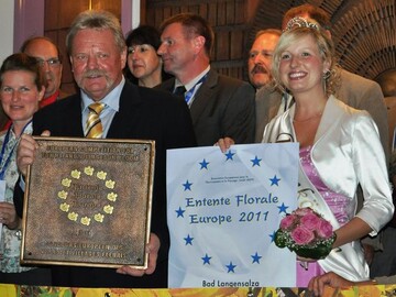 Brgermeister Schnau und die Rosenknigin prsentieren stolz die Plakette von Entente
Florale Europa.