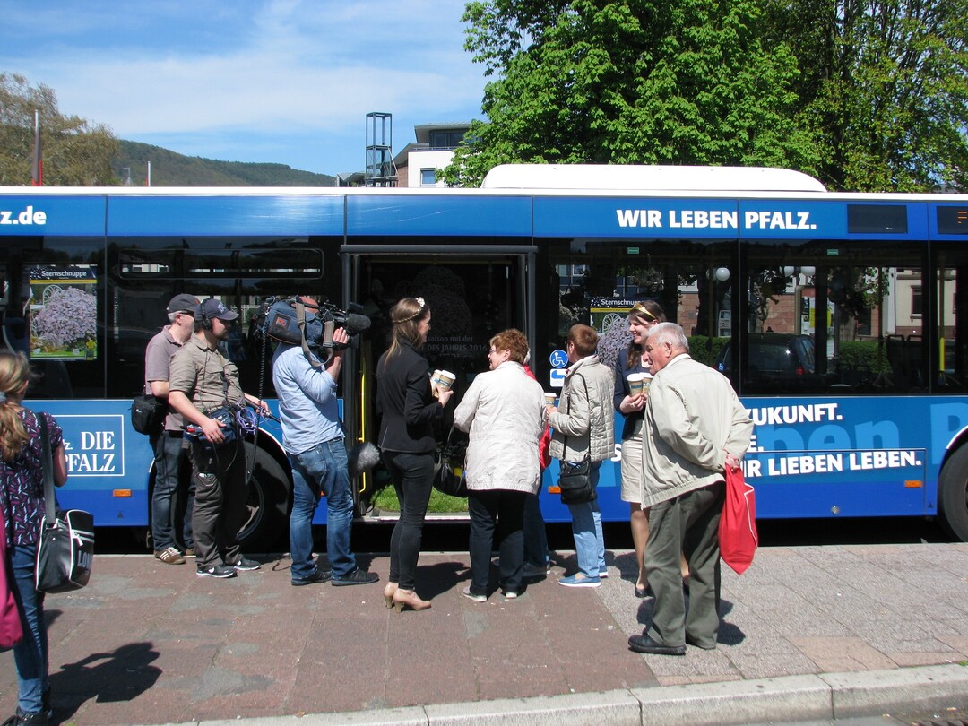 Katharina Schupp (Mitte) verteilt die blumigen Kaffeebecher an die Busfahrgste, beobachtet vom SWR Kamerateam