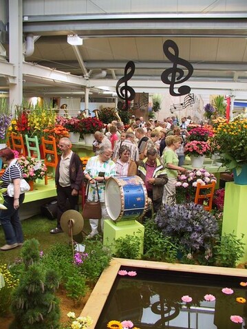 Spektakulre Gestaltung der Landgard-Rosen- und Gerberaschau. Sie stand unter dem Motto: Ein Sommernachtstraum wird wahr. Mit einer ganzen LKW-Ladung Musikinstrumente wurde der Stand zu einem italienischer Marktplatz mit einem durch die ausgestellten Blumen dargestellten Orchester.