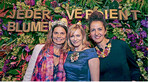 Sarah Wiener (links) und Gesine Cukrowski posieren mit Diadem und Brosche freudestrahlend vor der Blumenwand.
