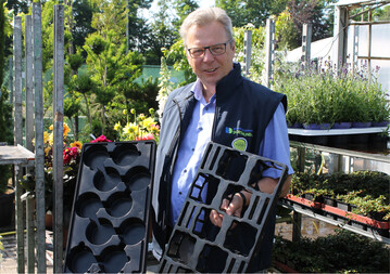 Der Dortmunder BGM-Geschäftsführer Herbert Kettermann mit geschlossenen Einweg-Wasserpaletten und offenen Mehrweg-Palettinos. In Dortmund werden für die Anlieferung in Einwegtrays 25 Cent für die Entsorgung berechnet. Dadurch wird mehr in Palettinos angeliefert.