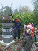 Friedhofsleiter Herbert Schimmel, Düsseldorf, und Rabe „Rudi“ erklären den Kindern die Bedeutung von Grabmalen