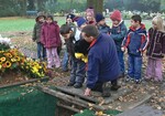 Der Rabe „Rudi“, Friedhofsleiter Herbert Schimmel und Kinder besprechen beim Kindertrauerprojekt an einem geöffneten Grab, wie eine Beerdigung abläuft.
