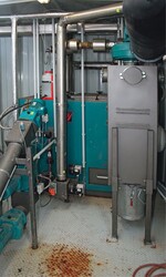 Links: Blick auf den Heizkessel, der mit Holzpellets beheizt wird. Links ist die Fördereinrichtung zu sehen – und dazwischen unser Autor Dr. Karl Schockert