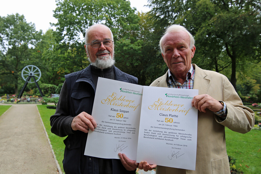 Klaus Szepan und Klaus Platte (v.l.n.r.) mit Goldenem Meisterbrief am Dauergrabgepflegten Gemeinschaftsgrabfeld der Firma Platte auf dem Ostfriedhof in Gelsenkirchen.