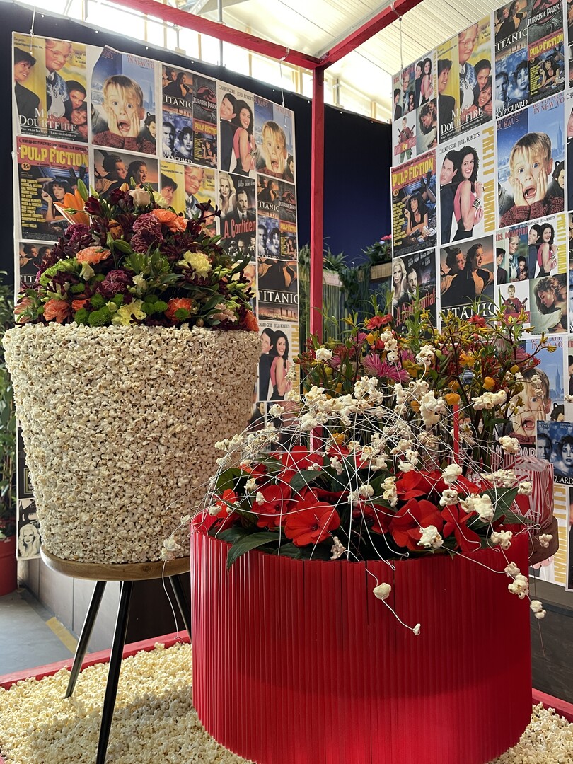 Hallenschau 7: Zurck in die Zukunft:Duftendes Popcorn, Rote Kinosessel und Filmplakate aus den 1990ern bilden die Kulisse fr florale Gestecke und Zierpflanzen.