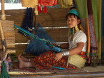 Die Padaung-Frauen weben Stoffe aus Baumwolle in traditionellen birmanischen Mustern, um ihren Lebensunterhalt zu verdienen. Die Minderheiten sind in Thailand zwar geduldet, jedoch bekommen sie kaum staatliche Unterstützung, müssen sich also den Touristen zur Schau stellen.
