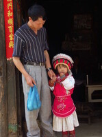 Ein Mädchen in traditioneller Bai-Tracht mit ihrem Vater kam vors Haus, um den fremden Mann zu betrachten.