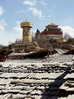 Blick von meinen Zimmer über die mit Holzschindeln gedeckten Dächer der alten tibetischen Häuser. Im Hintergrund ein Tempel und eine riesige Gebetsmühle. Sie zu drehen, bedurfte mehrere Männer
