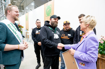 ZVG-Präsidentin Eva Kähler-Theuerkauf (rechts) und die Deutsche Blumenfee Hannes Schrader (links) überreichen den IPM-Publikumspreis an die Vertreter von Seedstockers / KK Farming für ihre kompakte Cannabis-Pflanze „BCN Critical XXL Autoflower“