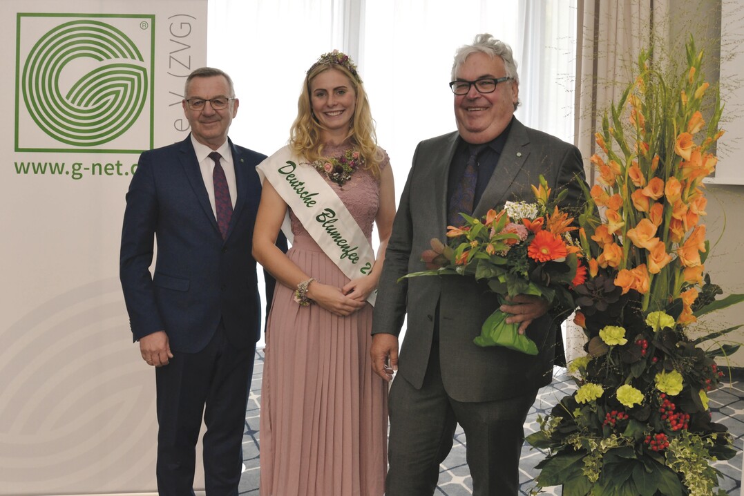 ZVG-Präsident Jürgen Mertz (links) und Blumenfee Annika Stroers gratulieren Wilhelm Böck zur Wiederwahl als ZVG-Vizepräsident.